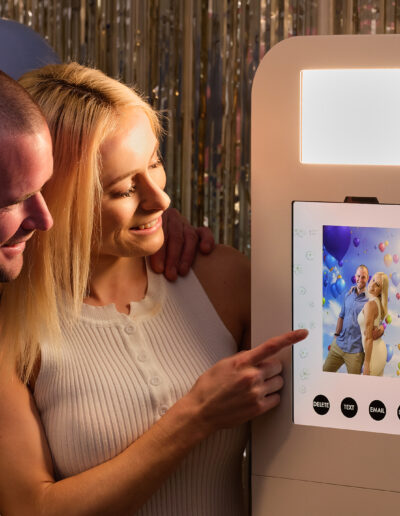 Ashley Photo Booth in action, couple looking at their picture with the balloon background